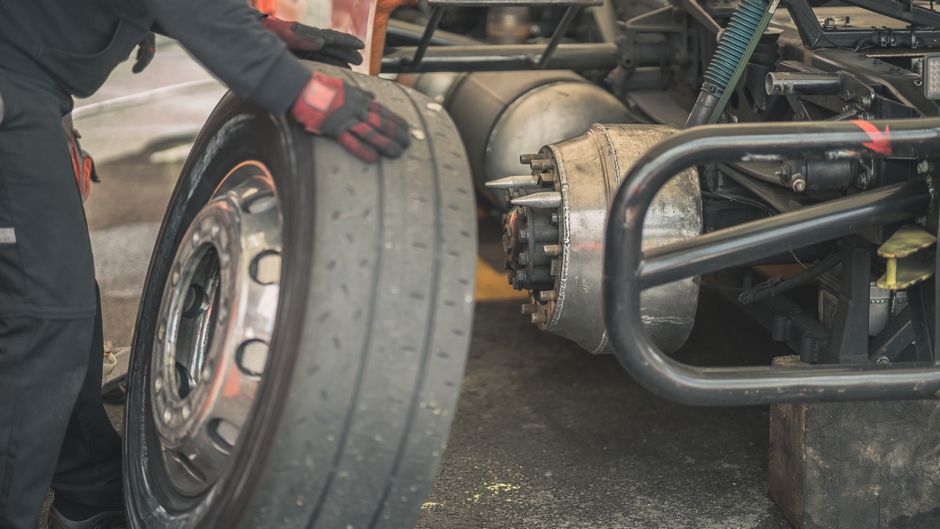 Mechanic working on replacing a tire in a professional automotive garage setting.